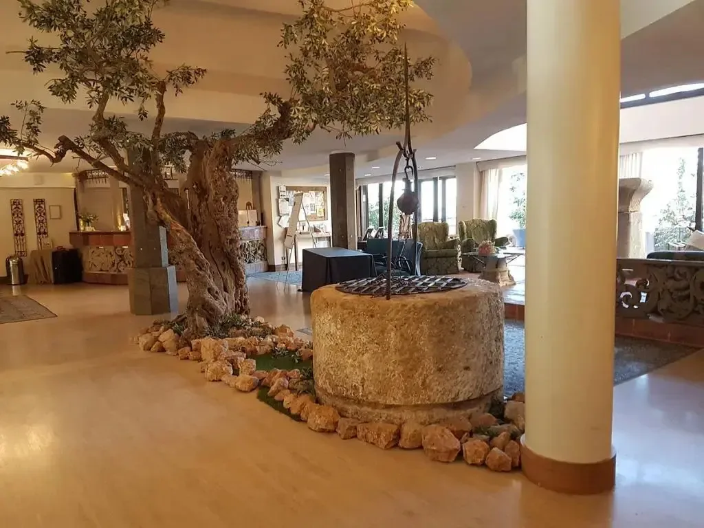 Hall dell'hotel con ulivo secolare, antico pozzo in pietra e zona salotto