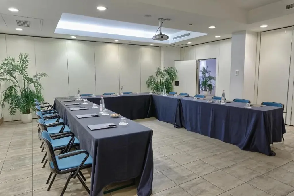 Sala meeting con tavoli disposti a ferro di cavallo, sedie e proiettore