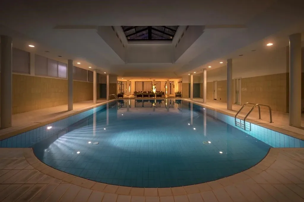 Piscina interna coperta con lucernario e zona salotto illuminata