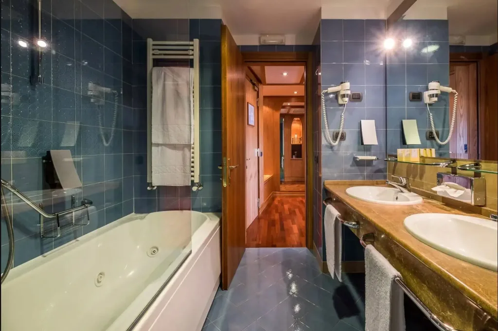 Bagno con vasca idromassaggio, doppio lavabo e piastrelle blu