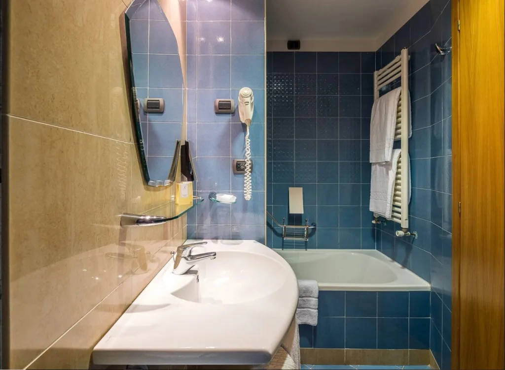 Bagno con lavabo, specchio, vasca e piastrelle blu e beige