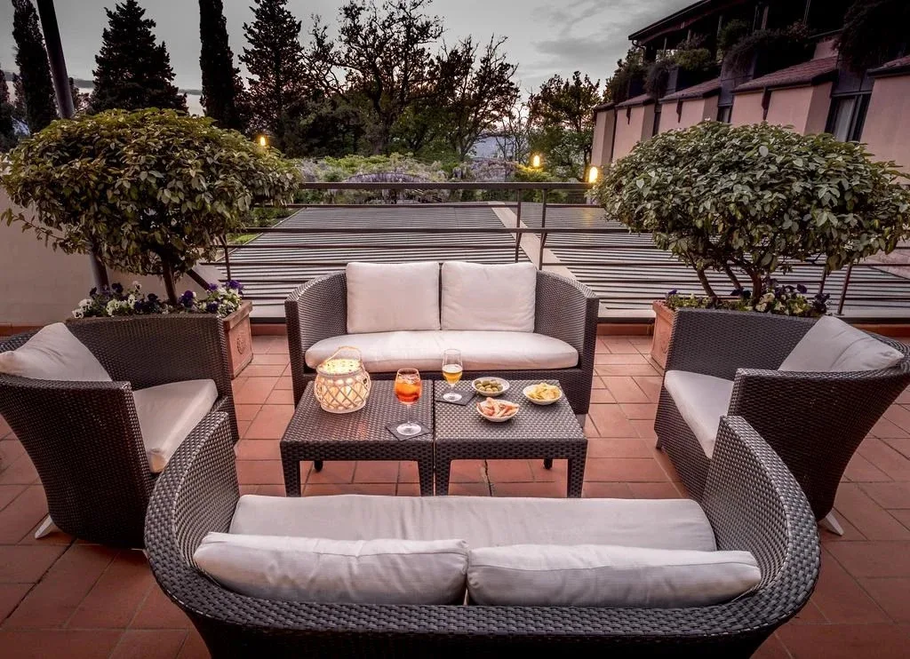 Terrazza esterna con divani in vimini, tavolino con aperitivo e piante