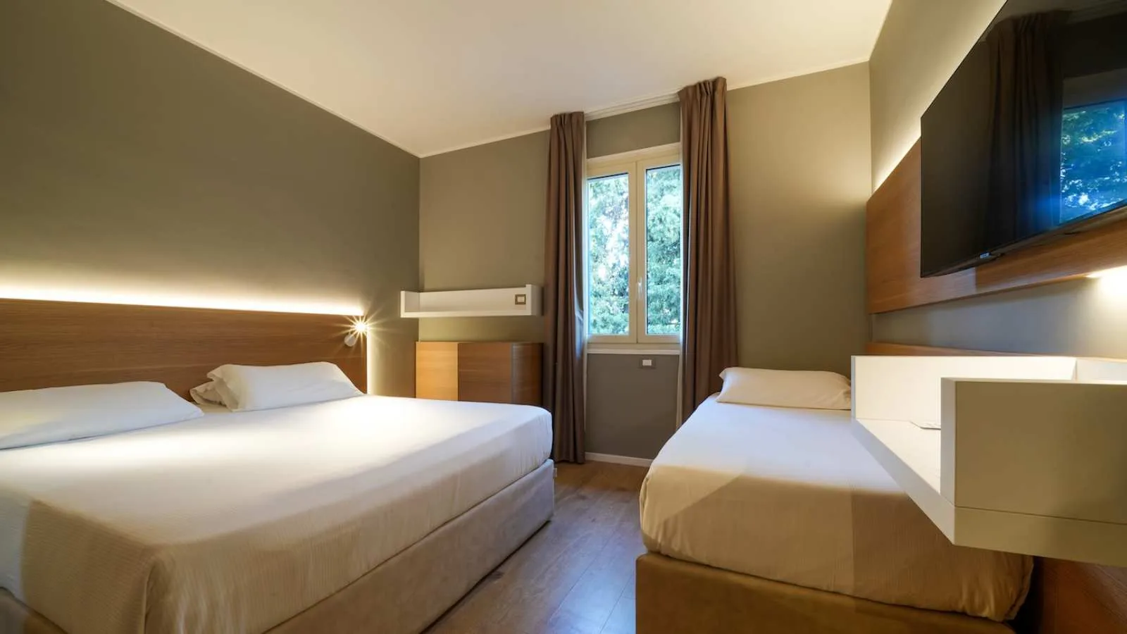 Camera di TH Lacona con letto matrimoniale, letto singolo, scrivania e televisore a parete.
