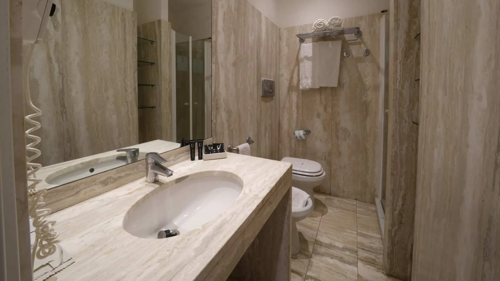 Bagno di una camera di TH Lacona con lavabo, specchio, asciugacapelli, doccia e set di cortesia.