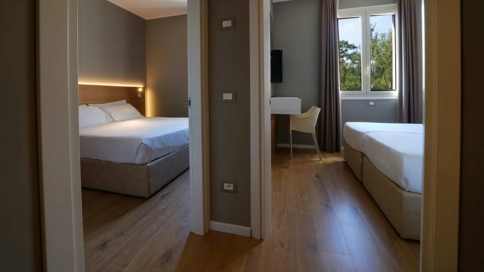 Veduta di due ambienti notte di TH Lacona, con letto matrimoniale e letti singoli.