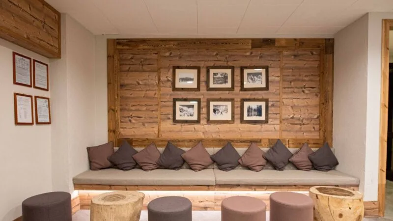 Immagine di una zona d'attesa con divano e cuscini su una parete di legno, decorata con sei foto in cornice.