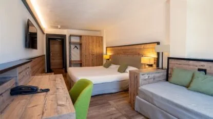 Camera moderna con letto, divano, scrivania, armadio e illuminazione calda in stile rustico.