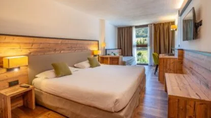Camera spaziosa con letto king-size, letti separati, scrivania, TV e vista panoramica sul verde.