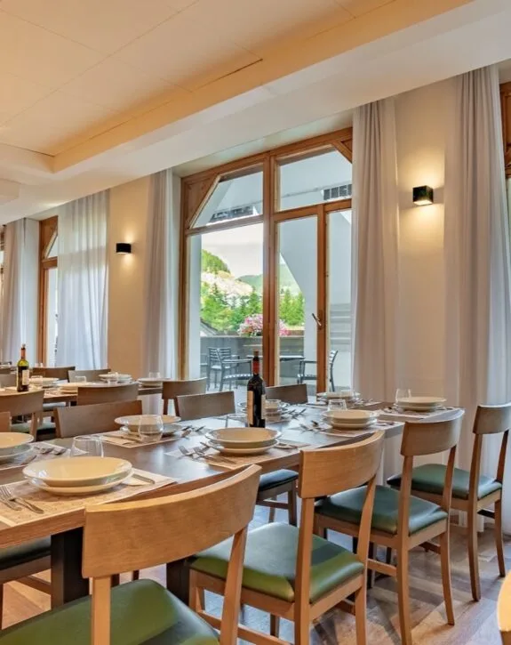 Sala da pranzo elegante con tavoli pronti, vista su balcone e pareti con luci accattivanti.