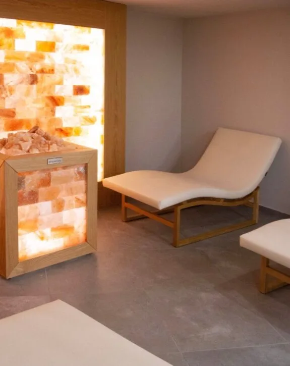 Poltrona in stile sauna con luce calda e parete di sale rosa.