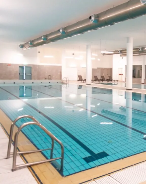 Piscina coperta vuota con sedie e tubo di aspirazione al soffitto.