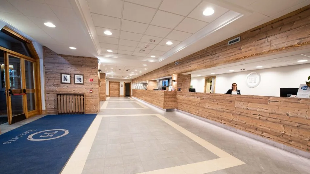 Reception dell'hotel con banco in legno e staff sorridente.
