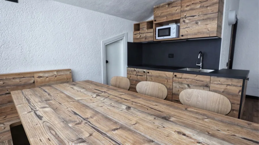 Cucina moderna con ante in legno, tavolo in legno naturale e sedie in stile minimalista.