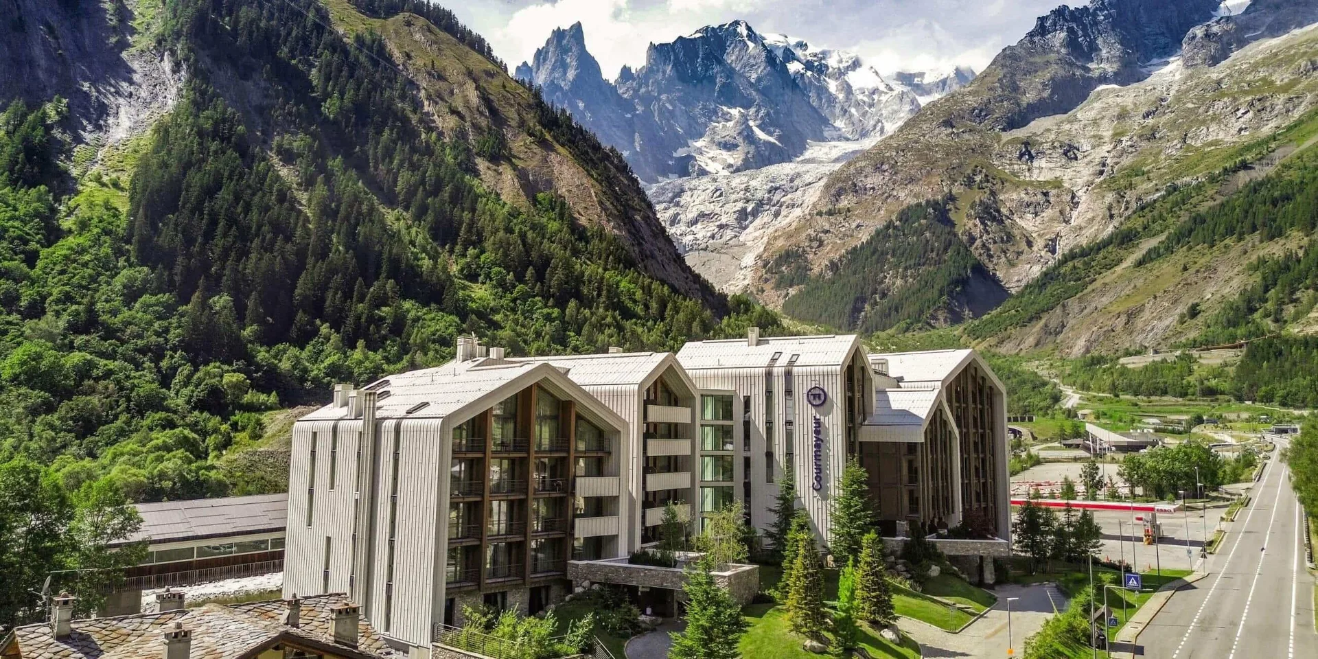 Veduta aerea dell'hotel circondato da boschi verdi e vette rocciose alpine