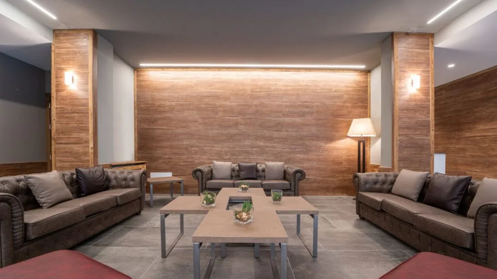 Salotto dell'hotel con divani chesterfield in pelle, tavolini e parete rivestita in legno