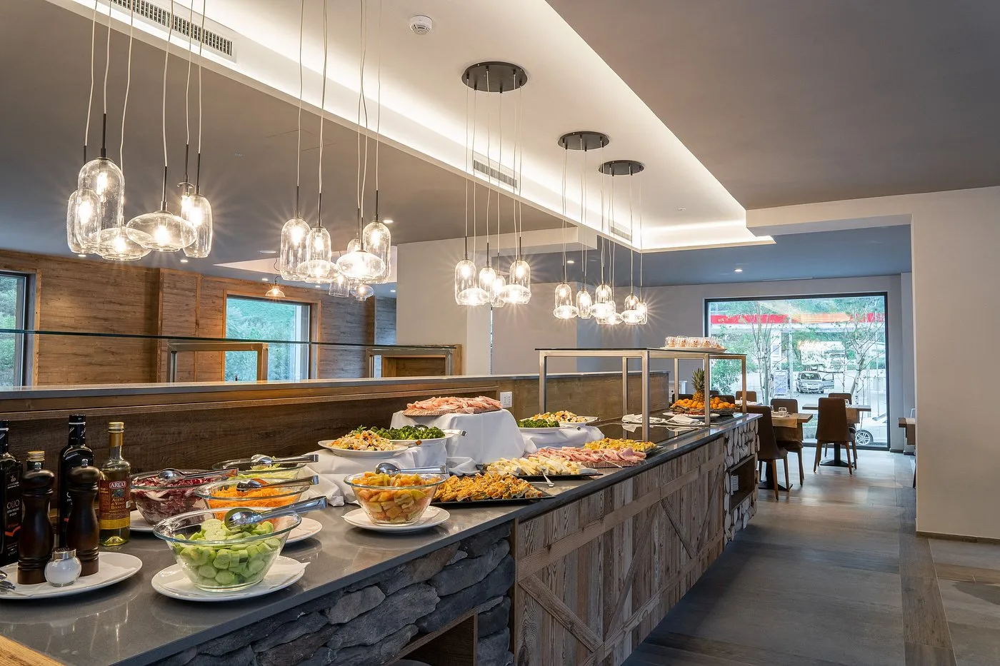 Buffet dell'hotel con piatti caldi, insalate e frutta sotto lampade a sospensione