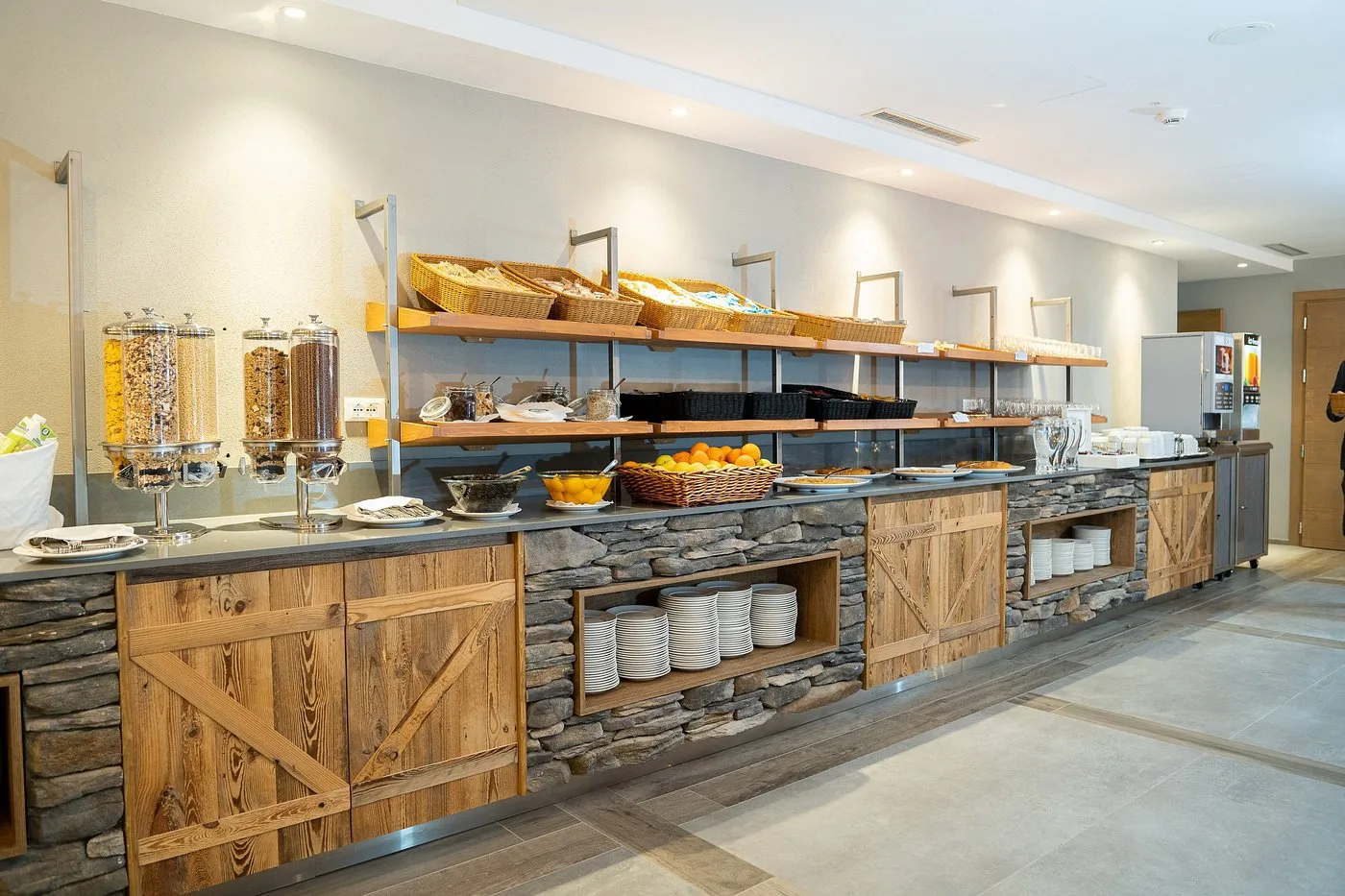 Buffet della colazione con cereali, cestini di pane e frutta su mobili in legno e pietra
