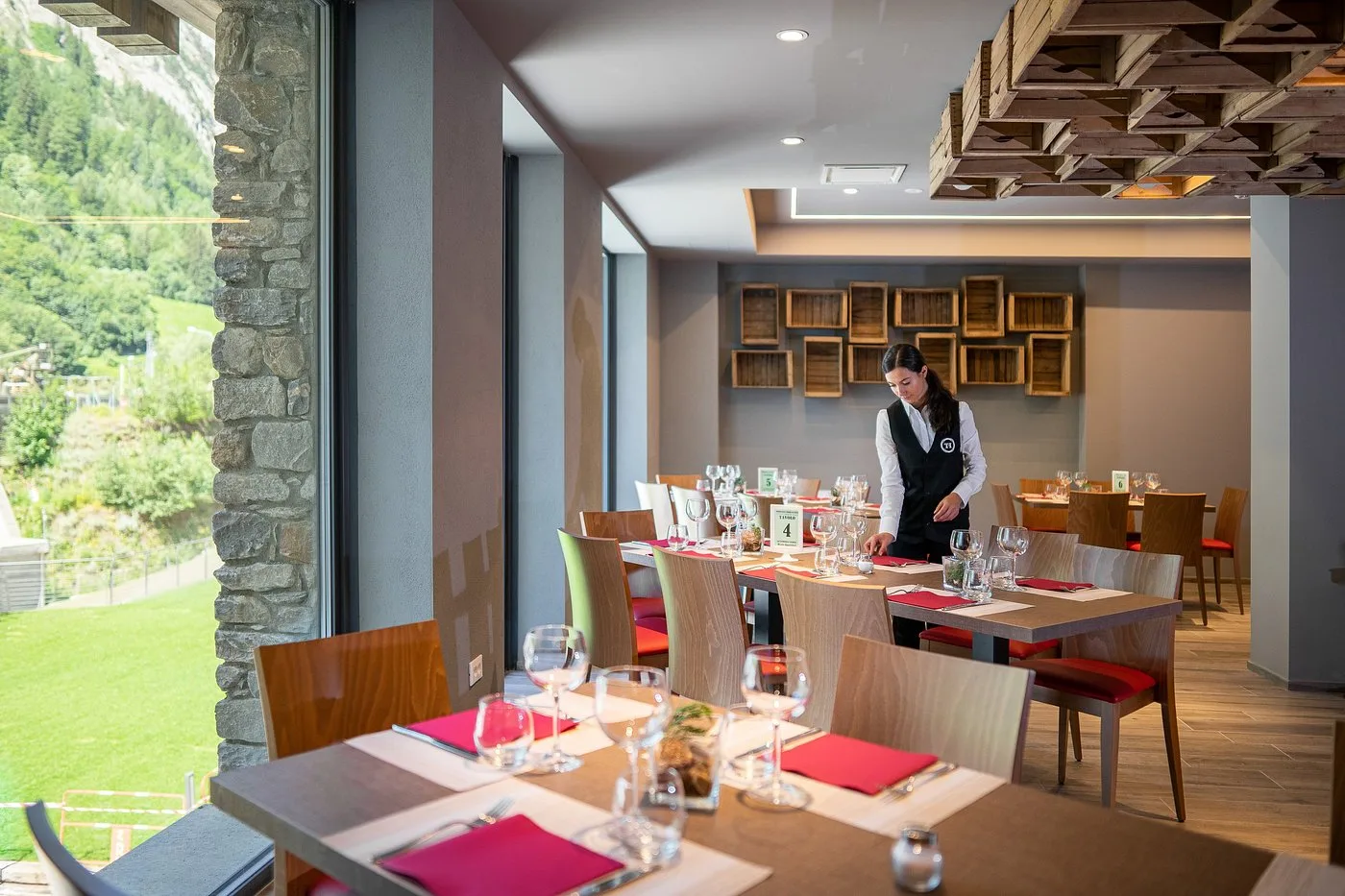 Sala ristorante dell'hotel con tavoli apparecchiati e vista sul verde attraverso ampie vetrate