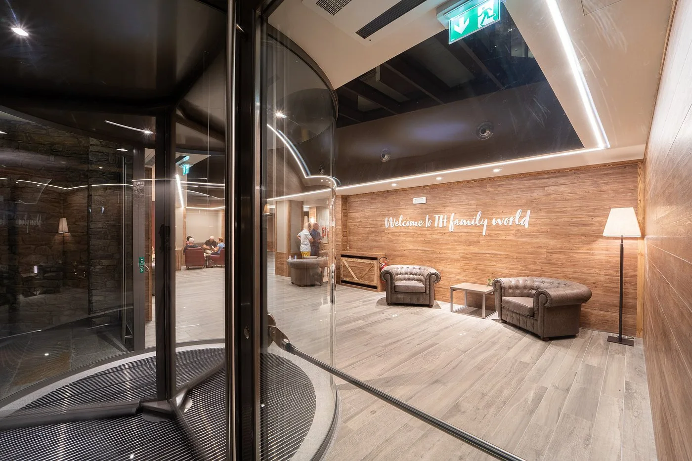 Ingresso dell'hotel con parete in legno, poltrone in pelle e scritta di benvenuto