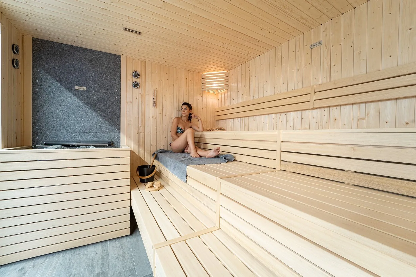 Donna che si rilassa nella sauna finlandese in legno chiaro dell'hotel