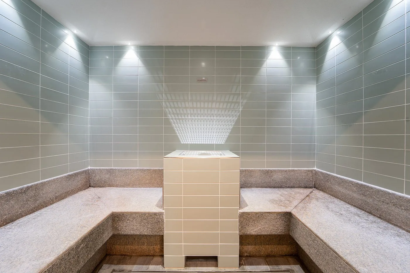 Bagno turco della spa con rivestimento in piastrelle e sedute in pietra