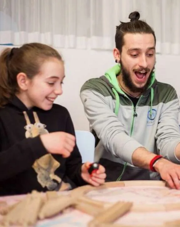 Ragazza e giovane uomo sorridenti giocano insieme a un gioco da tavolo con pezzi di legno su un tavolo.