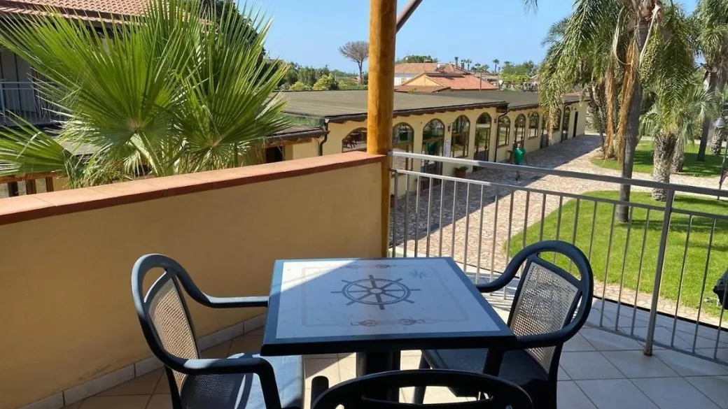 Balcone con tavolo decorato e sedie metalliche affacciato sul cortile e gli edifici dell'hotel