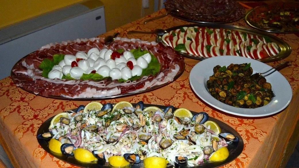 Buffet con piatti di salumi, mozzarella, insalata di mare e antipasti vari su tavolo decorato