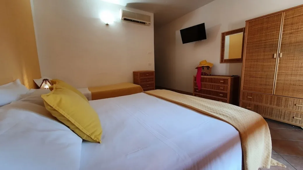 Camera con letto matrimoniale, TV a parete, armadio e cassettiera in vimini e aria condizionata