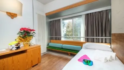 Camera con letto singolo, seduta verde e mobili in legno