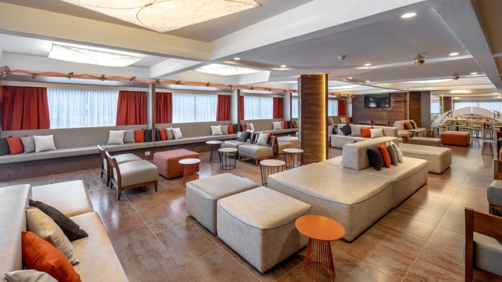 Ampia sala lounge con divani beige, cuscini colorati e tavolini di design