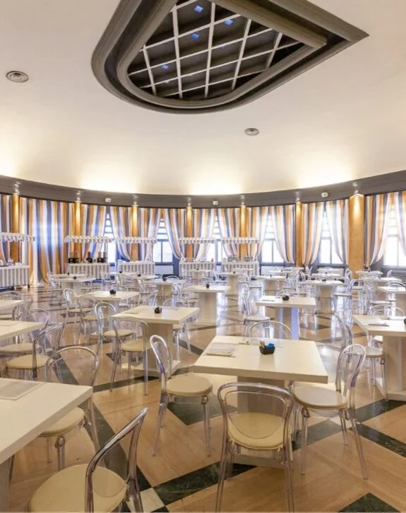 Sala da pranzo luminoso con tende rigate e sedie trasparenti in stile moderno.