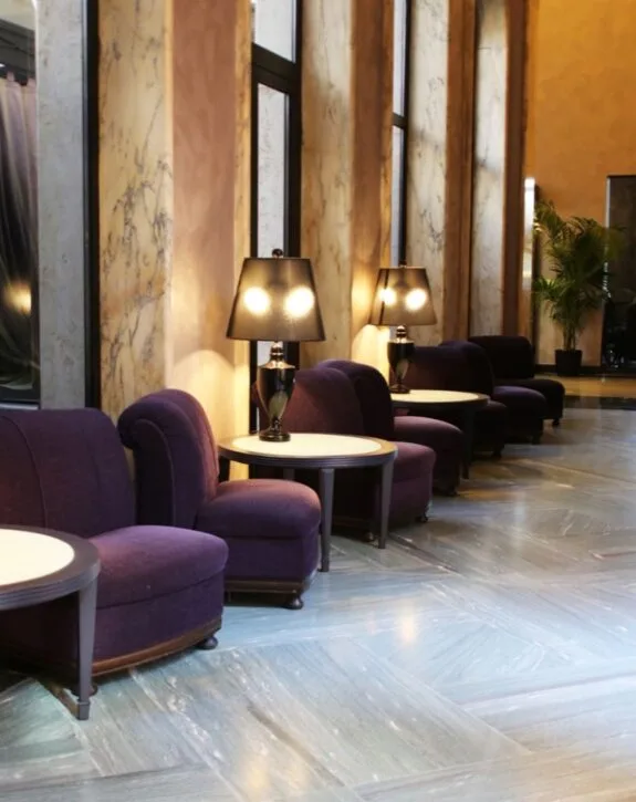 Sdraio viola con lampade da tavolo e pareti in marmo in un ambiente elegante e luminoso.