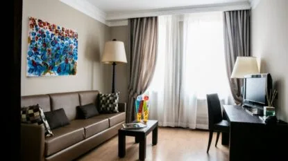 Soggiorno moderno con divano marrone, tavolino nero con decorazioni colorate, lampade e scrivania con computer.