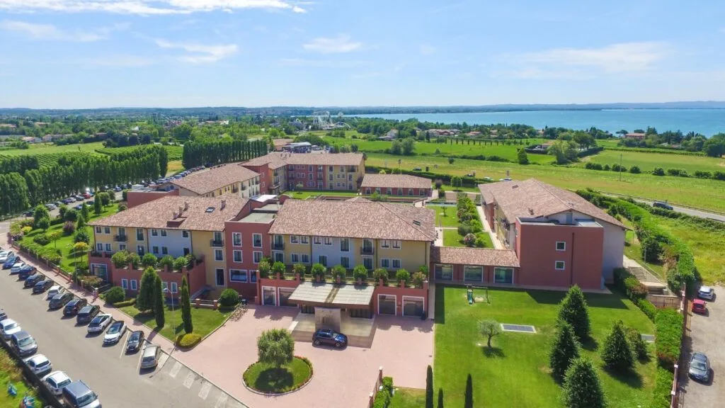 Complesso residenziale con appartamenti colorati, circondato da spazi verdi e vista sul lago e la campagna.