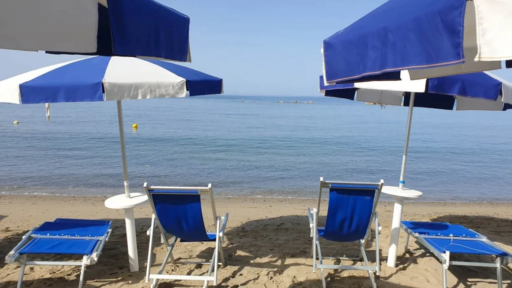 Lettini e ombrelloni blu sulla spiaggia con vista sul mare