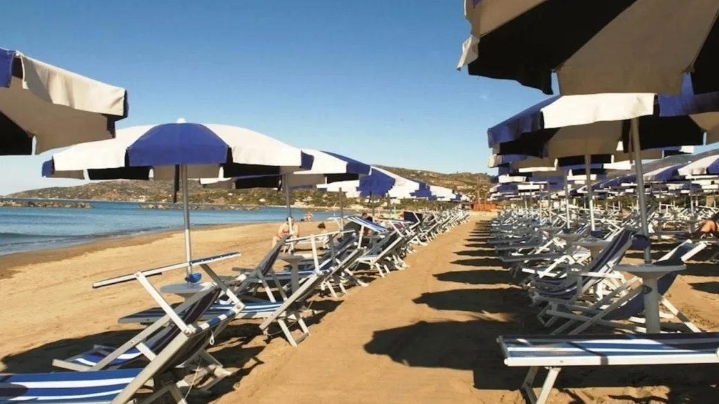File di lettini e ombrelloni blu e bianchi sulla spiaggia sabbiosa