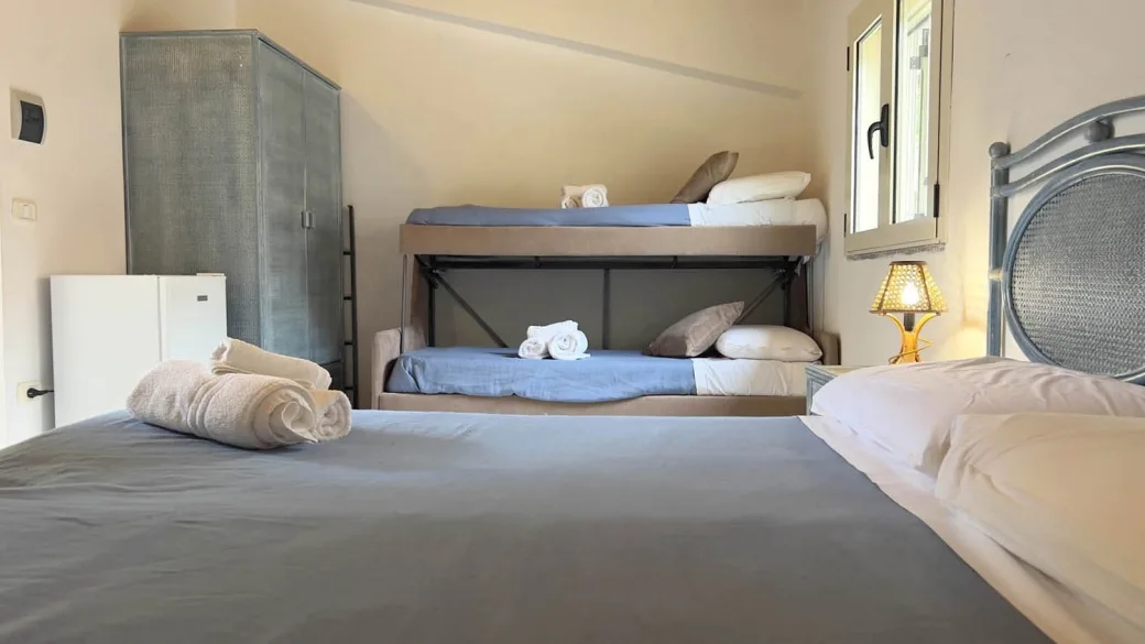 Camera con letto matrimoniale e letti a castello, armadio e asciugamani arrotolati