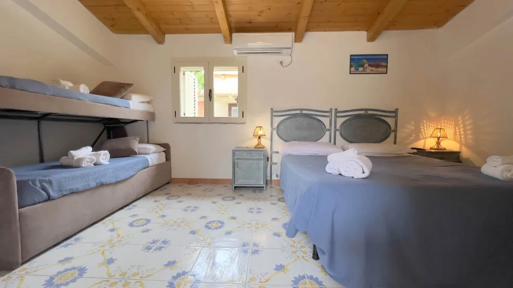 Camera con letto matrimoniale e letti a castello, soffitto in legno e pavimento decorato