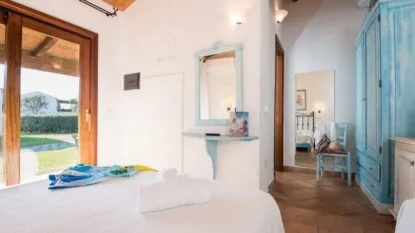 Stanza con mobili blu, specchio e porta vetrata che apre su un giardino.