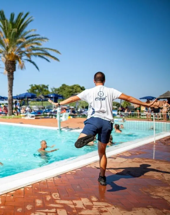 Staff di piscina che aiuta i bagnanti vicino alla vasca all'aperto sotto il sole.