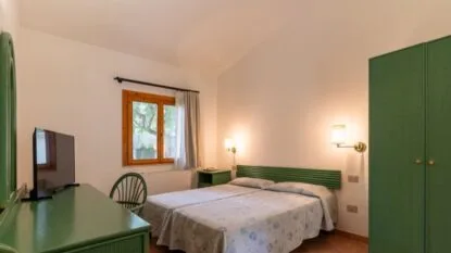 Camera da letto con due letti singoli uniti, mobili verdi, finestra con tenda bianca e pareti bianche.
