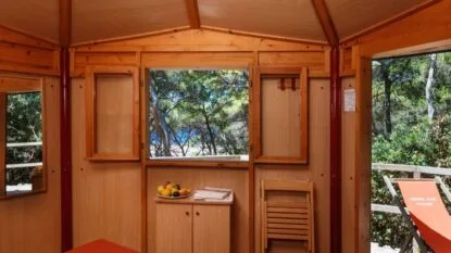 Interno di una baita di legno con vista sulla natura e un balcone.