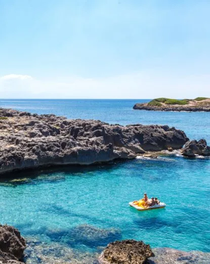 Gruppo di persone su una barca nel mare cristallino vicino a scogli러.