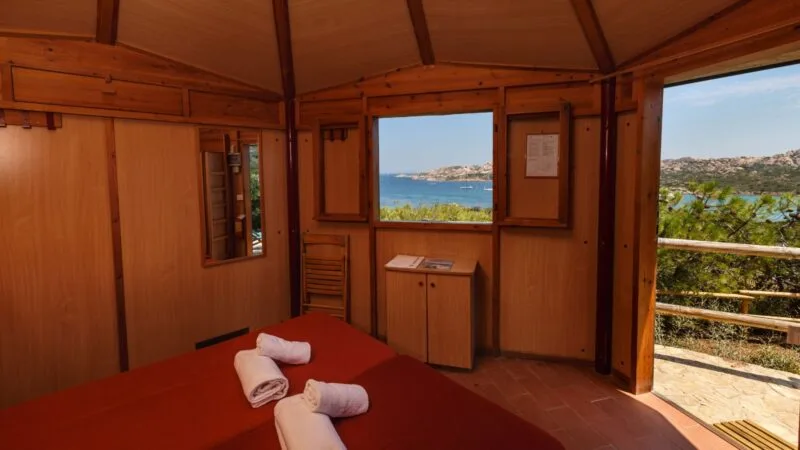 Interno di una camera di legno con vista sul mare e sulla natura circostante.