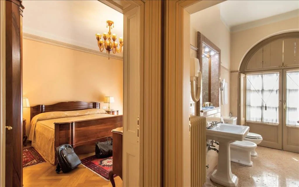 Camera con letto matrimoniale in legno e bagno adiacente con lavabo e bidet in stile classico