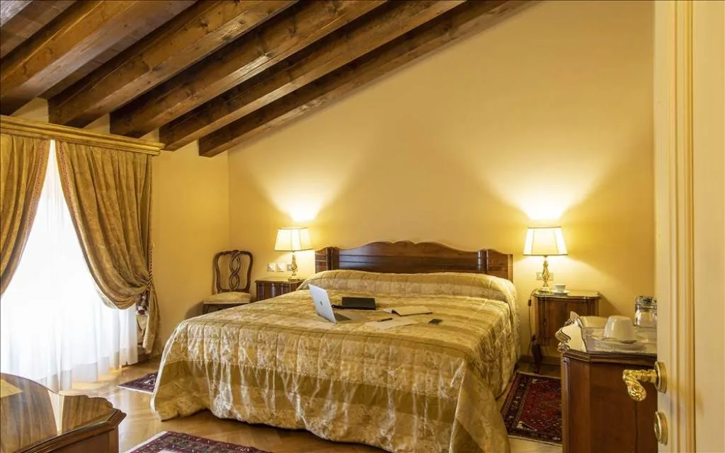 Camera mansardata con travi in legno a vista, letto matrimoniale e arredi classici