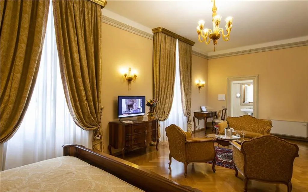 Camera con zona salotto, tende dorate, divano e poltrone in stile classico