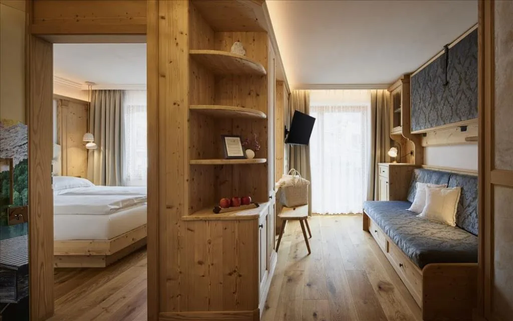 Suite con arredi in legno naturale, zona notte e divano