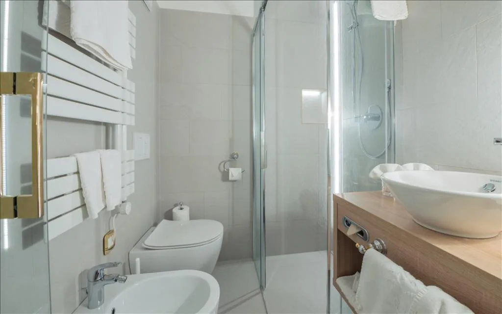 Bagno moderno con doccia, sanitari bianchi e lavabo su mobile in legno